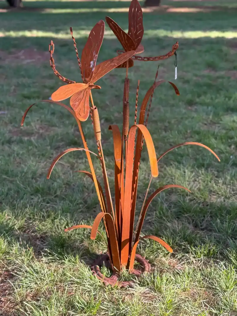 Corten steel dragonflies and bull rushes sculpture in a sunlit garden